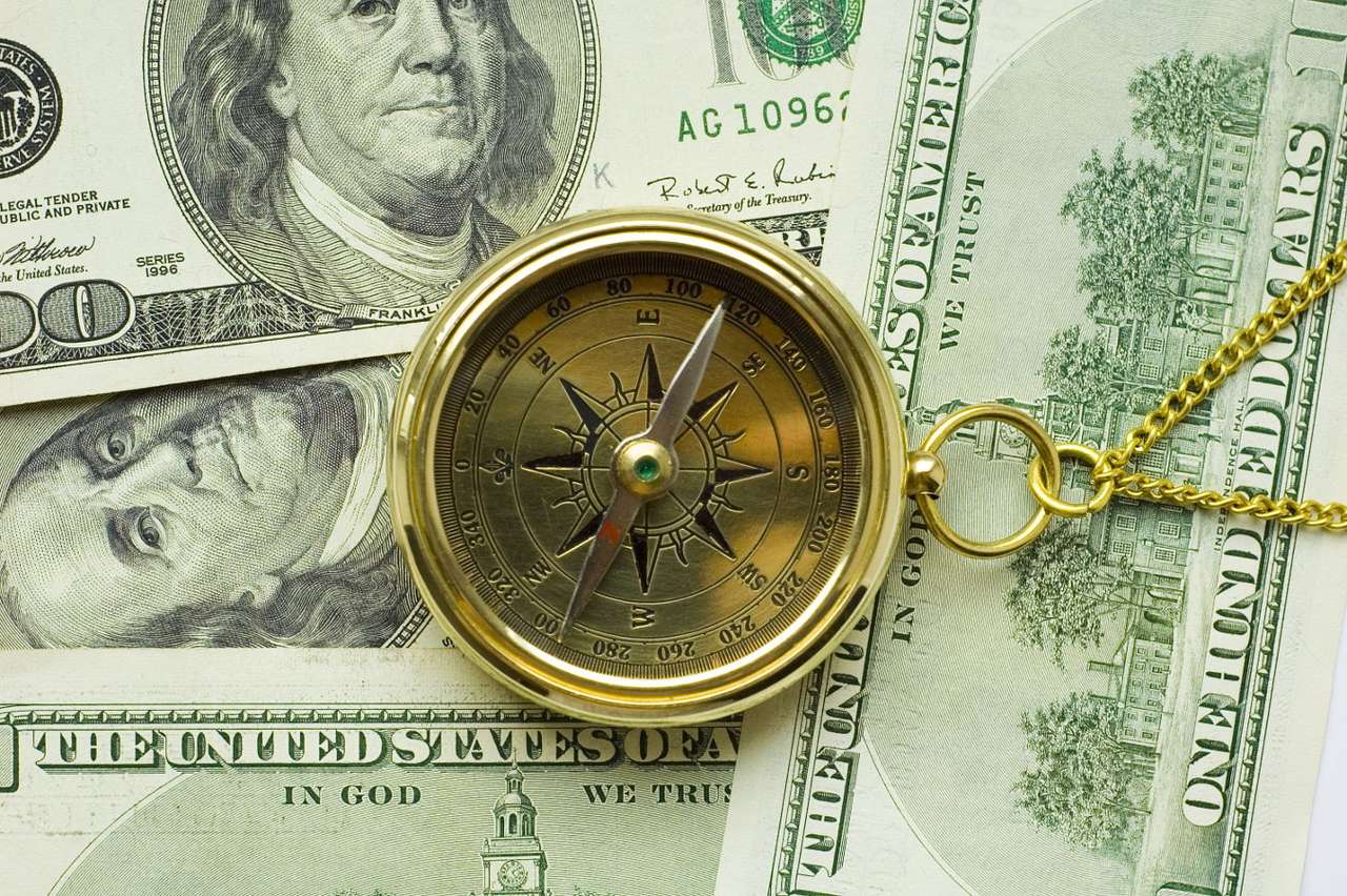 Stary kompas leżący na banknotach dolarowych puzzle