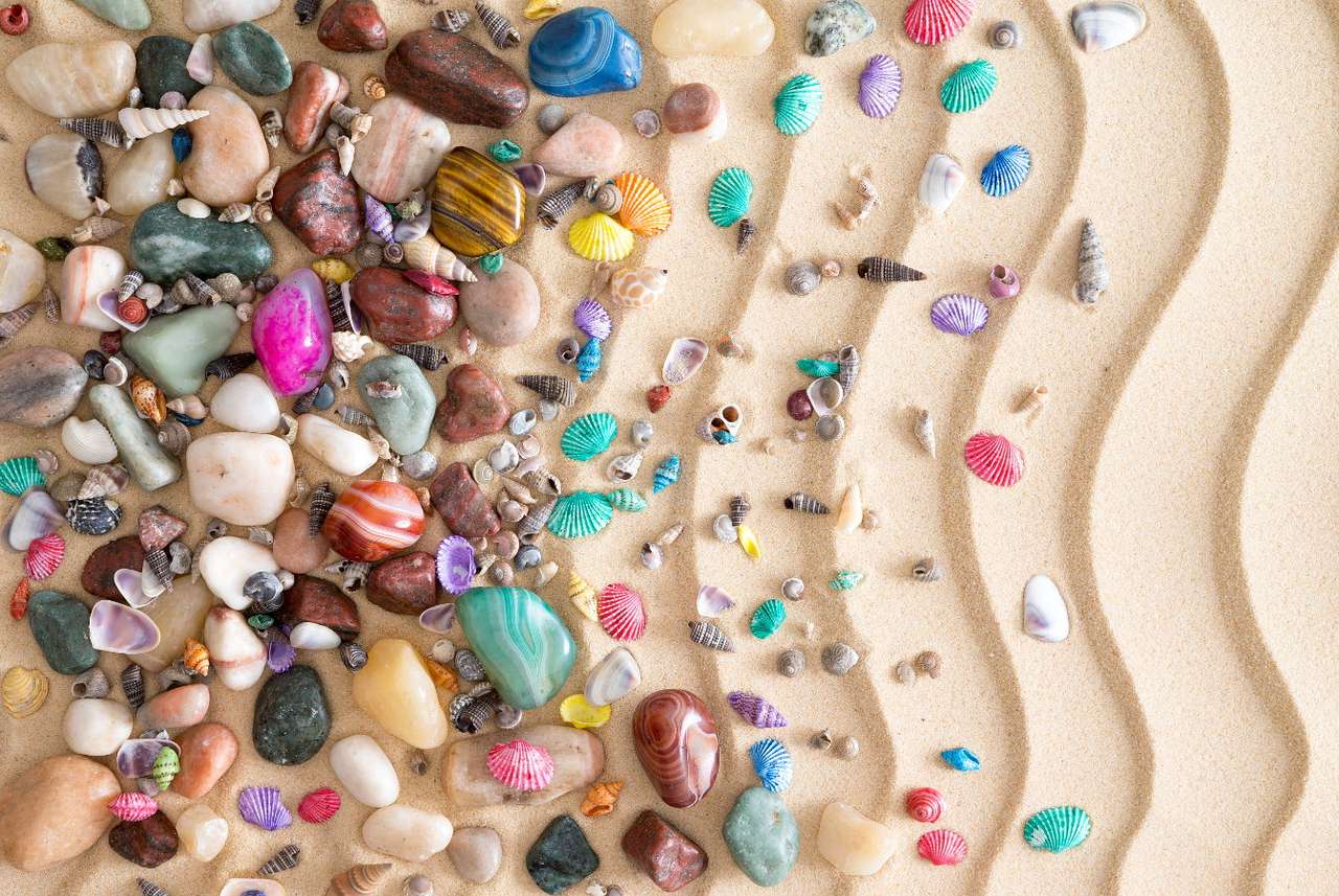 Kolorowe kamyki i muszelki na uformowanym przez fale piasku puzzle ze zdjęcia