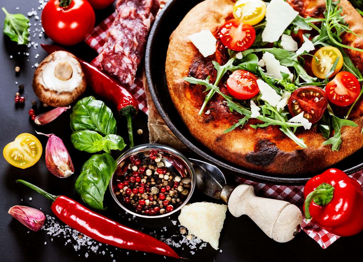 Pizza i świeże warzywa na czarnym stole puzzle online ze zdjęcia