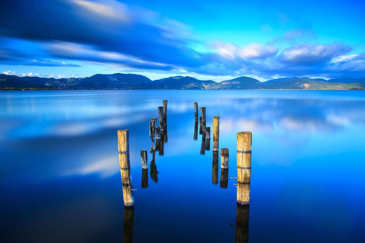 Drewniane molo lub molo pozostaje na niebieskim jeziorze zachód słońca puzzle online