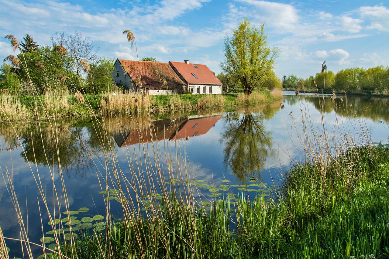 Dom nad rzeką, drzewami i błękitnym niebem. Piękny wiosenny krajobraz w Polsce puzzle online ze zdjęcia